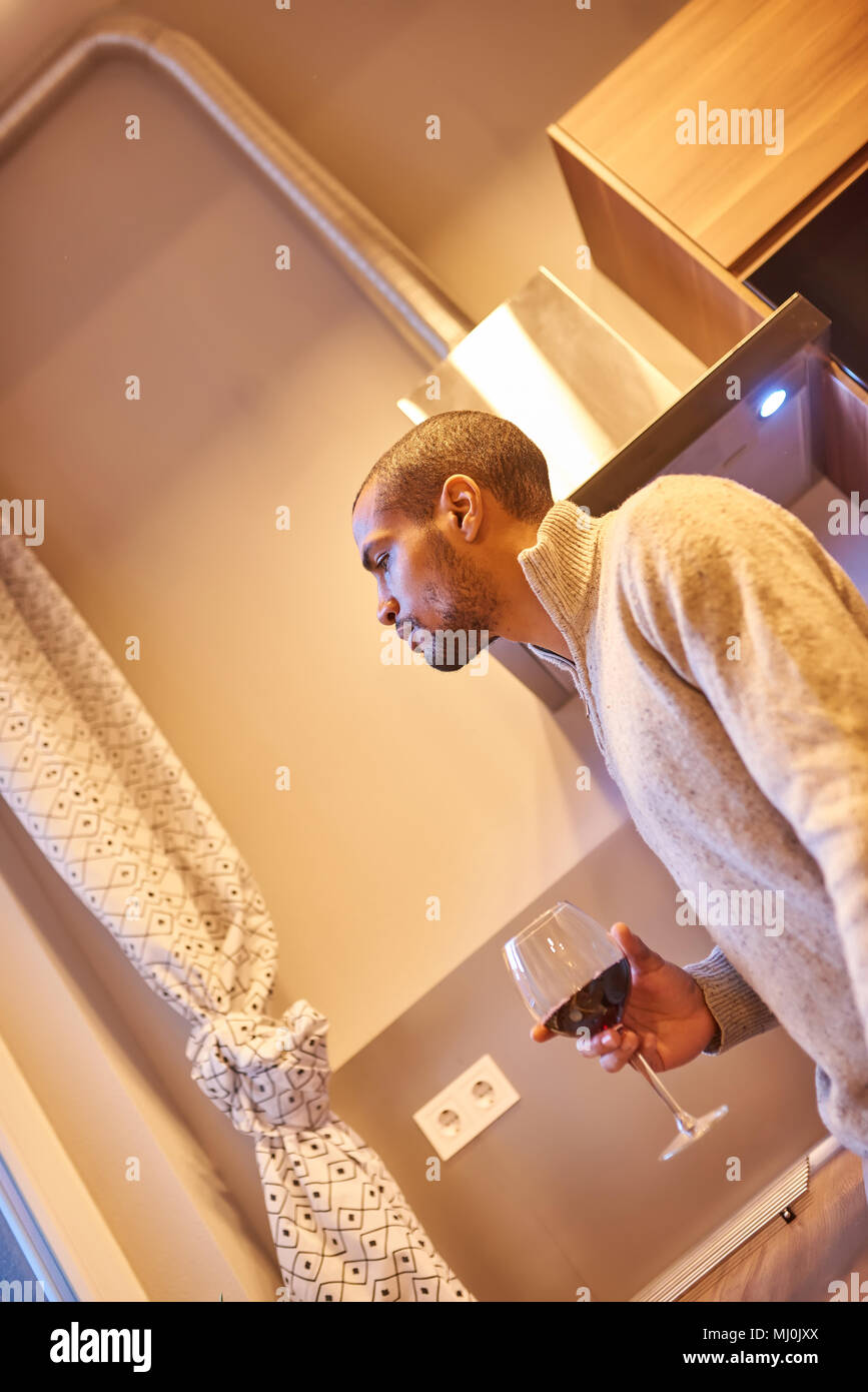 A serious handsome young man drinking wine in the kitchen Stock Photo ...