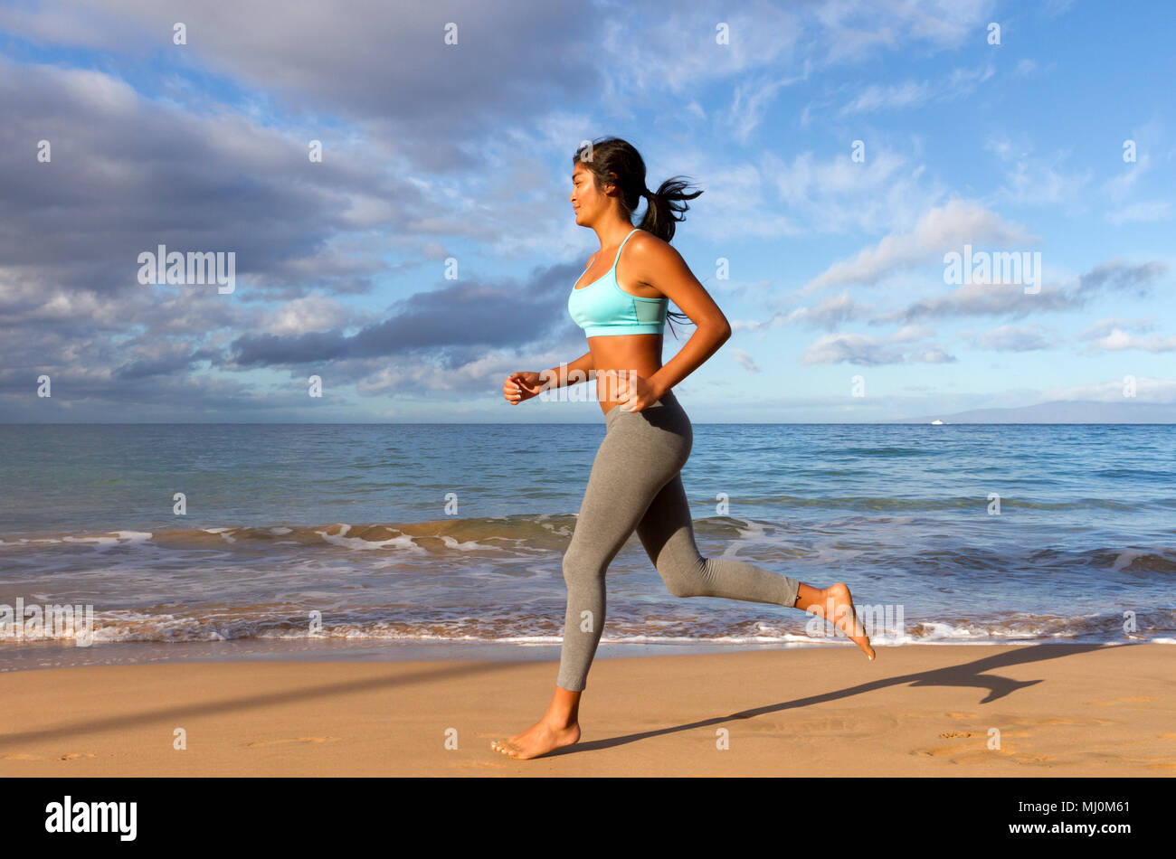 Hispanic female runs at the beach in Kihei, Maui, Hawaii. Stock Photo