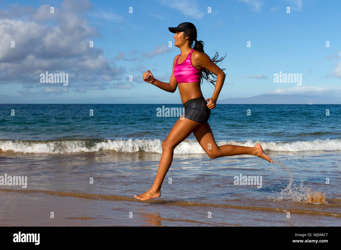 Hispanic female runs at the beach in Kihei, Maui, Hawaii. Stock Photo