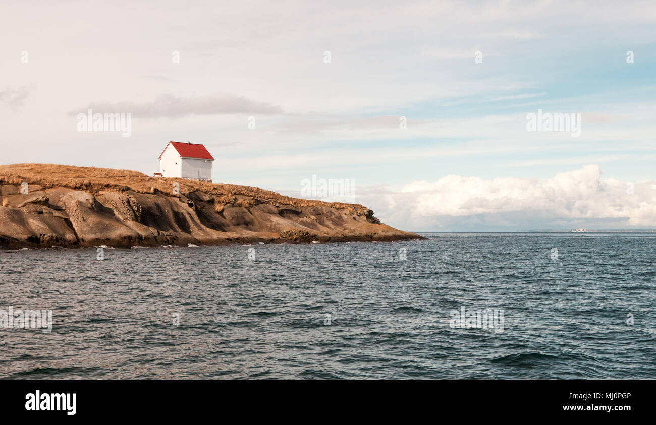 Landscape photography of a white house with red roof built next to the sea. Stock Photo