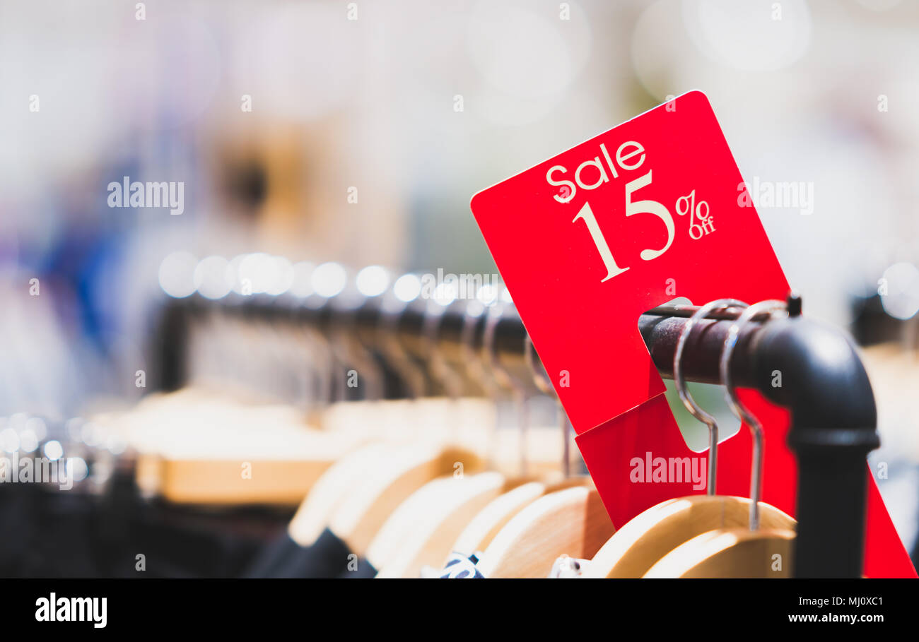 Red sale sign 15% discount on clothing rack in modern shopping mall or department store with copy space. Retail shop promotional event concept Stock Photo