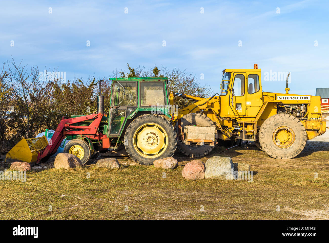 Gillberga, Oland, Sweden - April 7, 2018: Travel documentary of everyday life and environment. Two tractors parked beside the road, a green John Deere Stock Photo