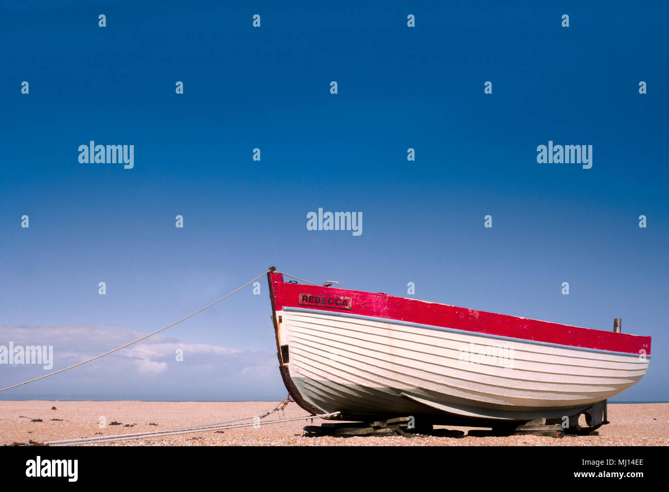 A wooden fishing boat named REBECCA being restored on the shingle beach ...