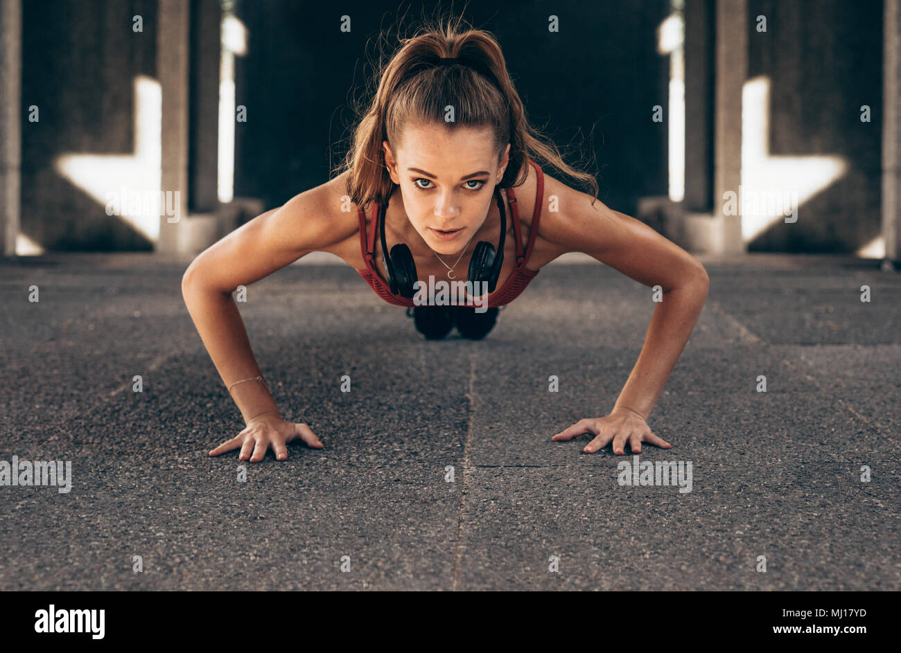 Fit young woman doing push ups exercises outdoors. Sportswoman doing core exercises. Stock Photo