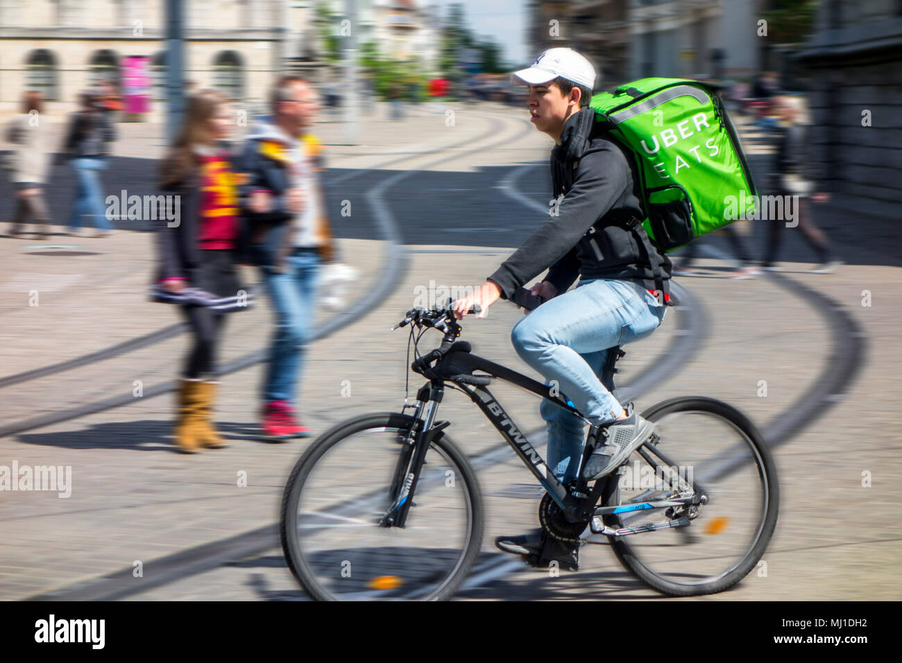 UberEATS / Uber Eats online meal ordering and delivery platform, bicycle courier delivering meals in the city center Stock Photo
