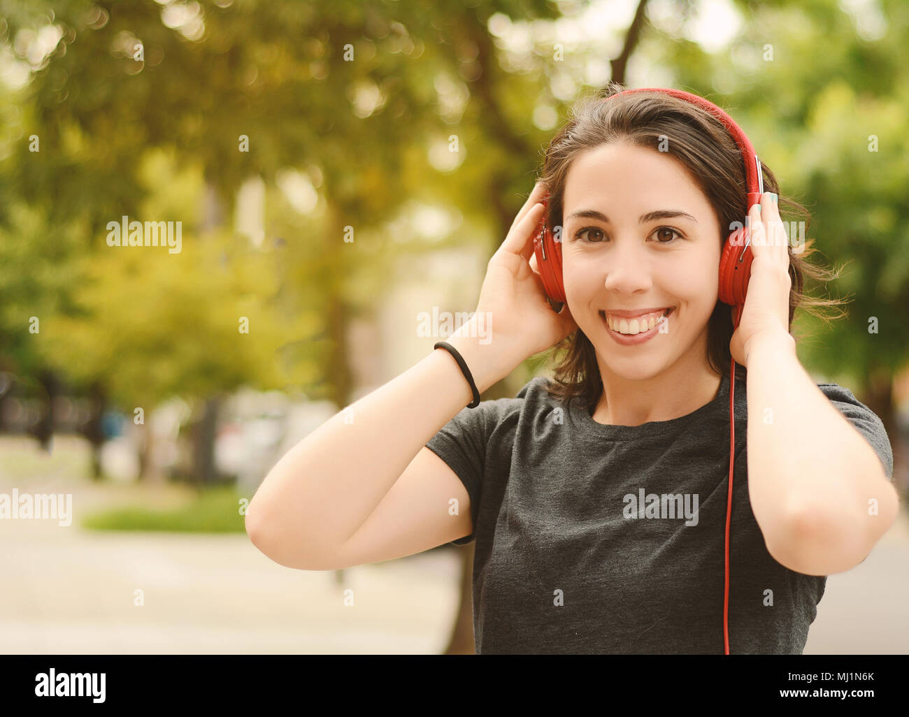 Portrait of young beautiful woman with red headphones listening music ...