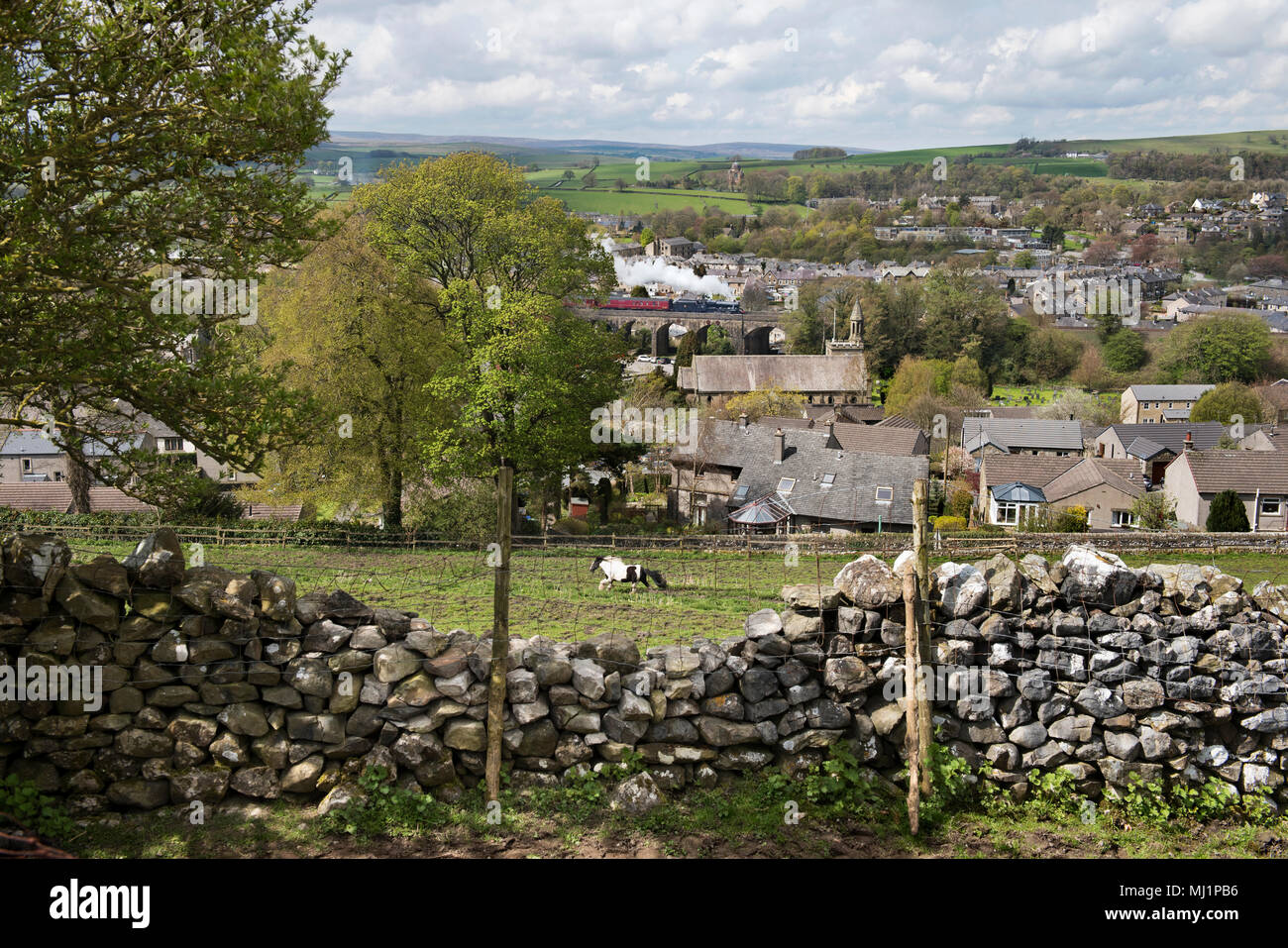 A steam train special passes over the viaduct in the centre of the Yorkshire Dales town of Settle, UK. Stock Photo
