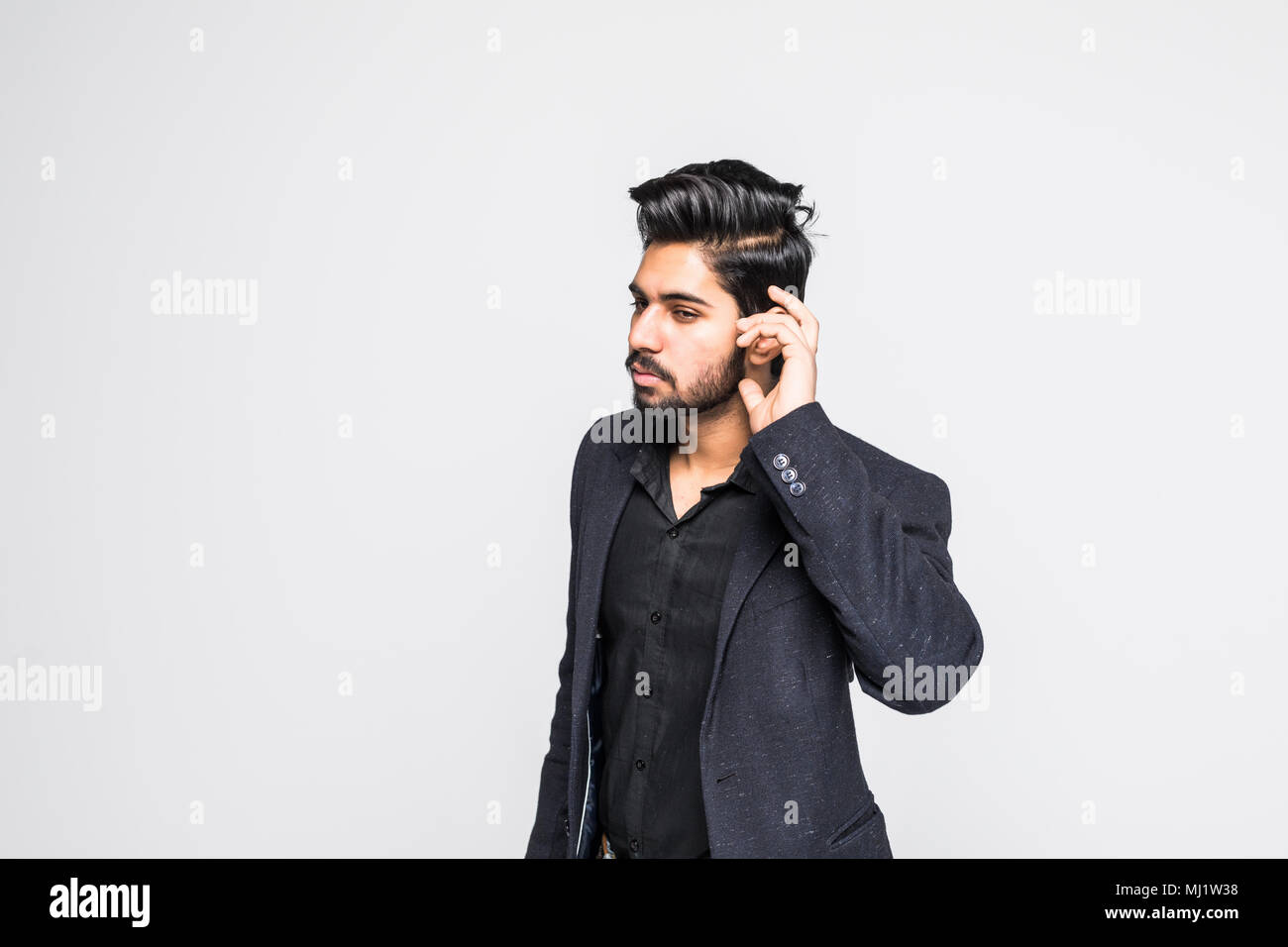 Closeup portrait of handsome indian guy trying to secretly listen in on a conversation, privacy violation, isolated on white background Stock Photo
