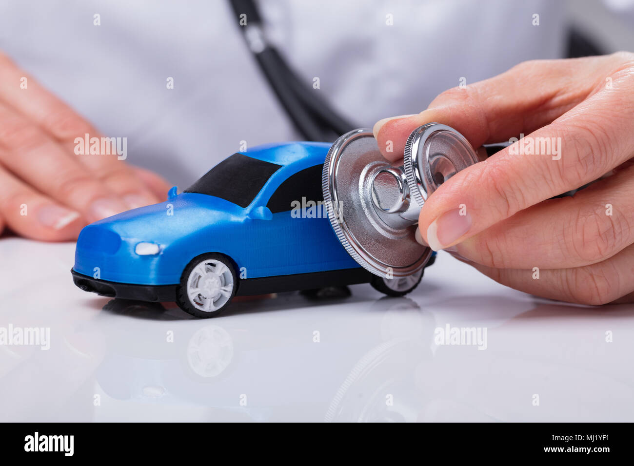 Doctor's Hand Examining Blue Car With Stethoscope Stock Photo