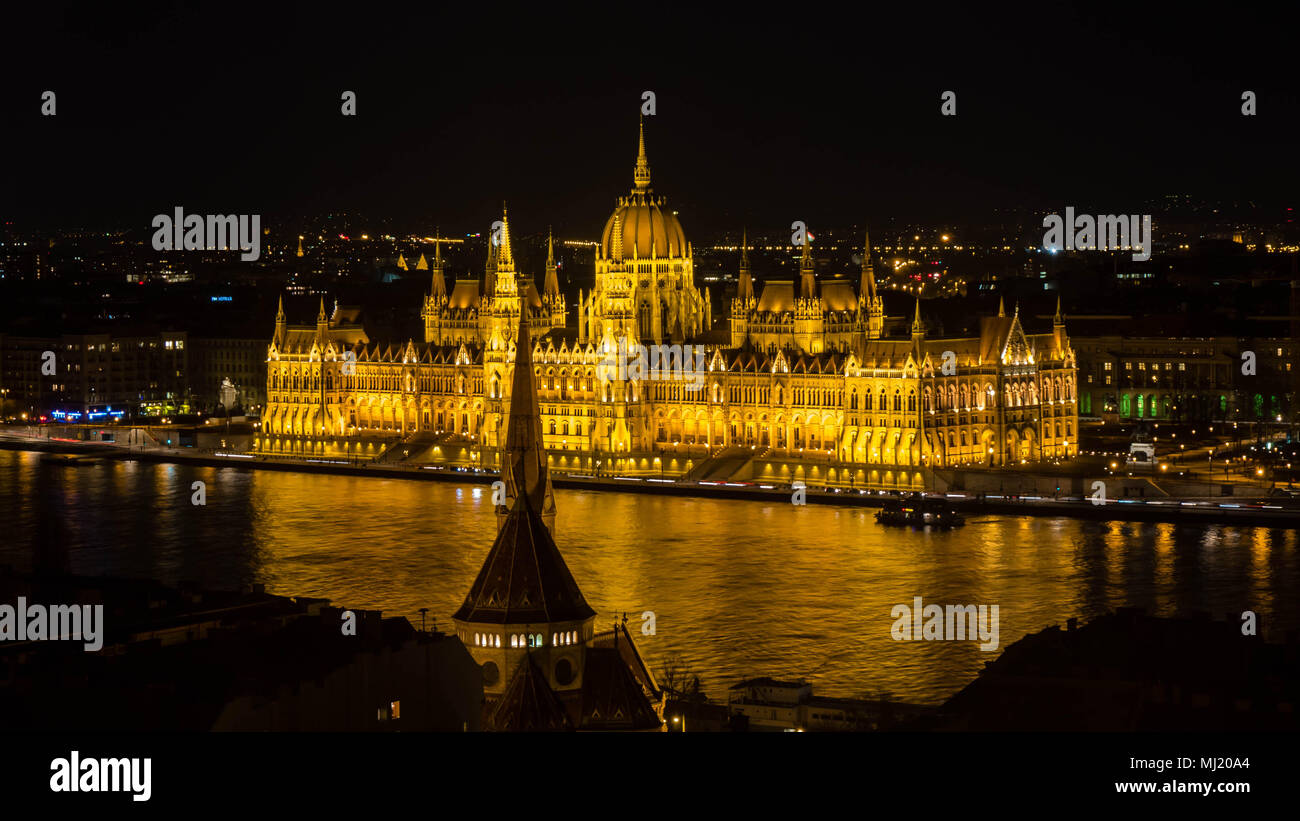 Golden Parliament of Budapest at night with river Danube seen from opposite river bank Stock Photo