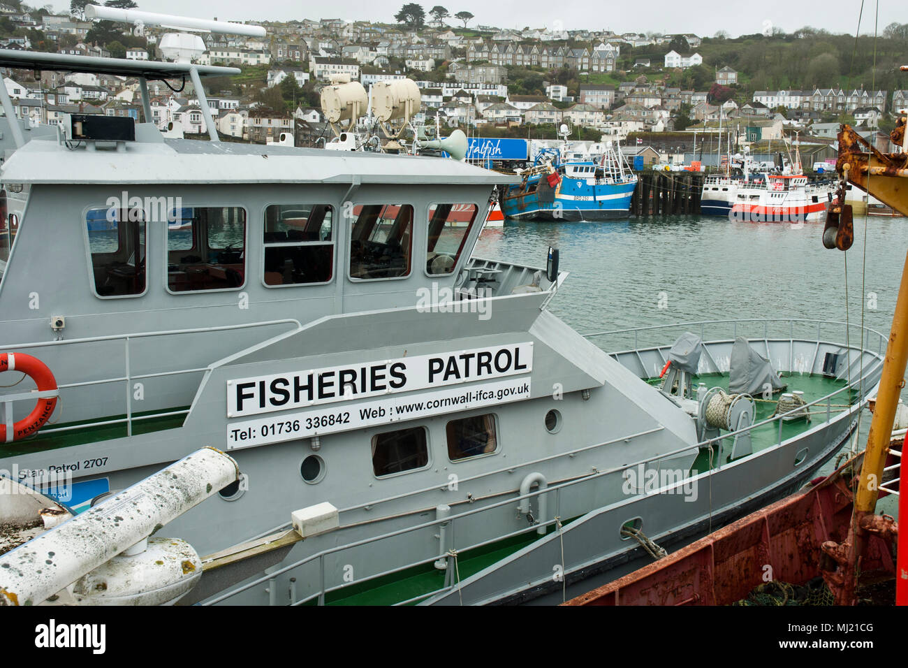 The Fisheries Patrol vessel, Saint Piran, in the foreground with fishing boats and the town of Newlyn in the background. Stock Photo