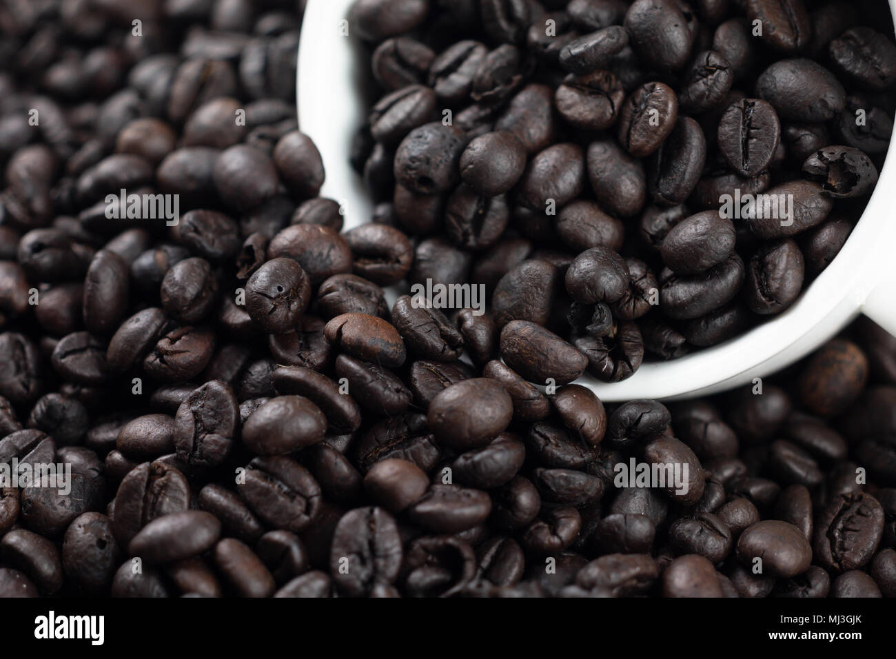 Roasted coffee beans in white glass. Placed on the coffee background and texture. Select focus shallow depth of field. Blurred background Stock Photo