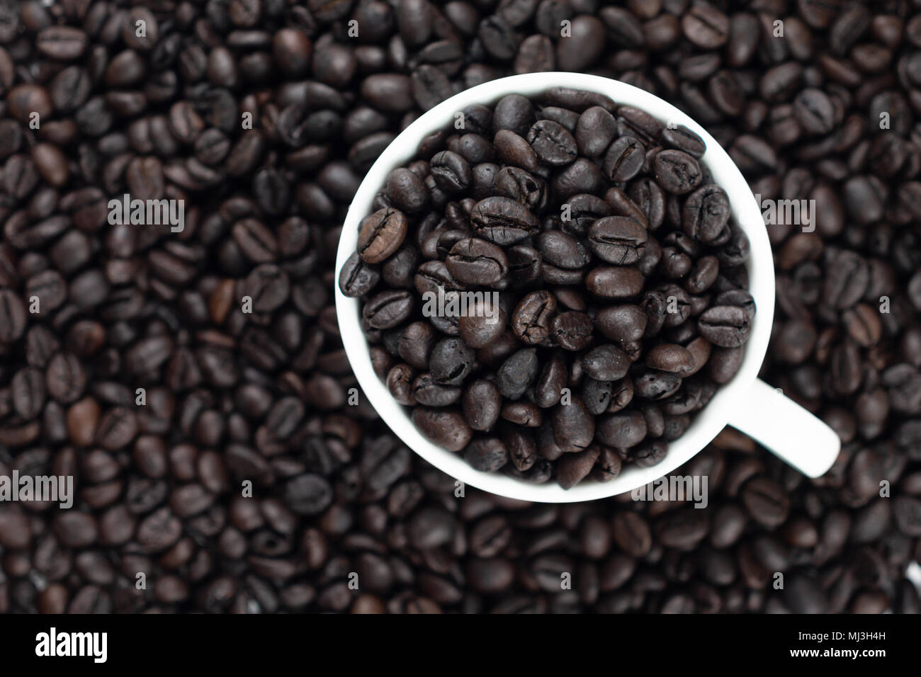 Roasted coffee beans in white glass. Placed on the coffee background and texture. Select focus shallow depth of field. Blurred background Stock Photo