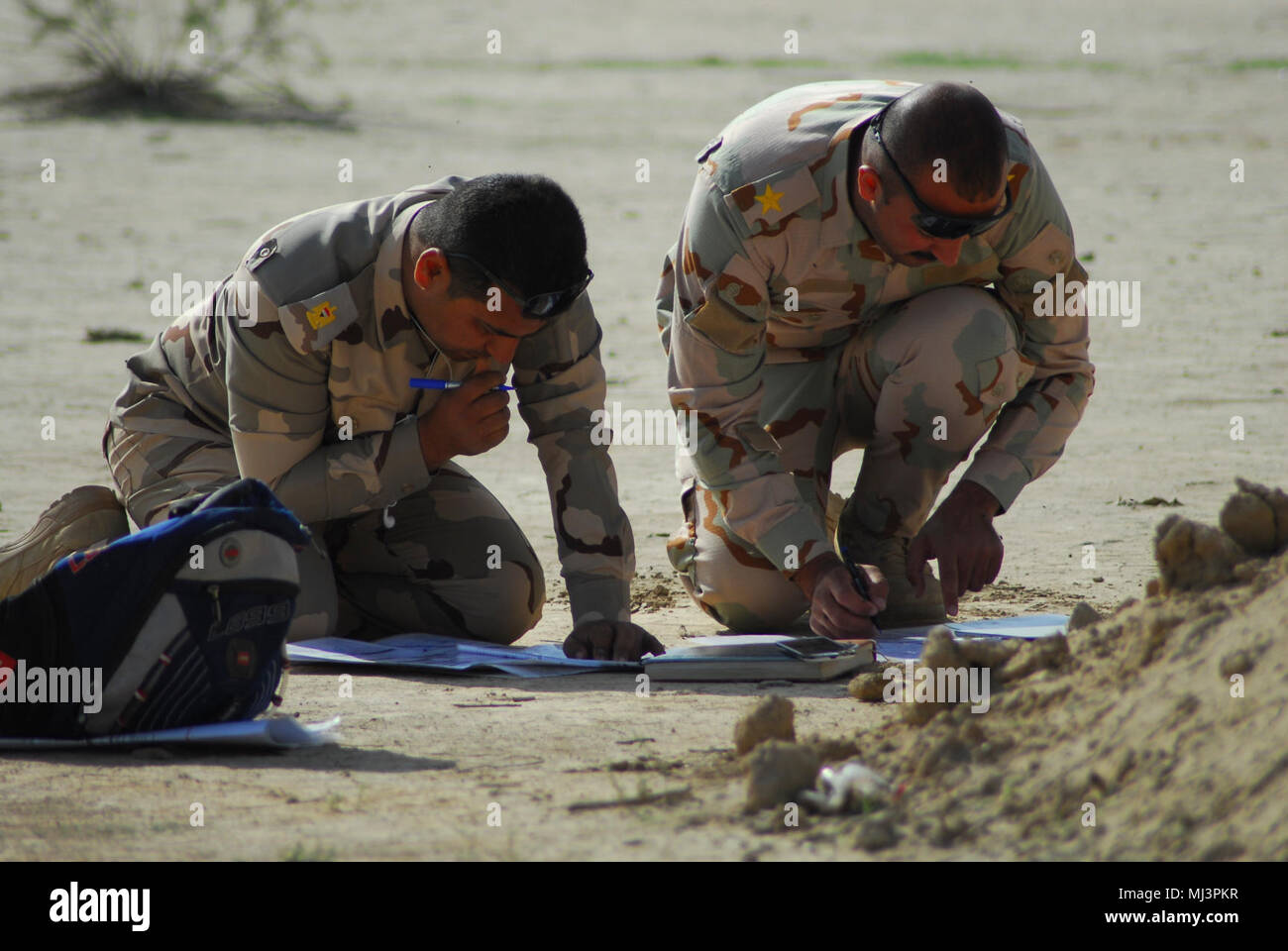 Iraqi Army students plot grid coordinates on a map, which they will use to instruct pilots assigned to the 7th Battalion, 17th Cavalry Regiment, 449th Combat Aviation Brigade, to simulate a close combat attack, involving an attack helicopter maneuvering and firing in direct support of a ground force coming into direct contact with the enemy during the Iraq Forward Air Control Course live-fire training exercise March 8, 2018 in Besmaya, Iraq.  The U.S. Army, U.S. Air Force, the New Zealand army and the Australian army partnered with Iraqi security forces students as part of a three-month course Stock Photo