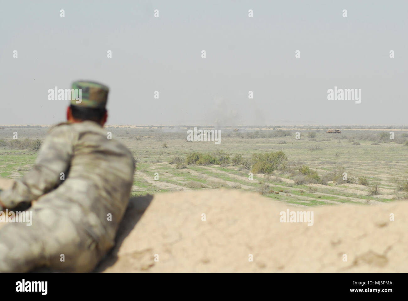 An Iraqi Army student observes the destruction of enemy forces in a simulated close combat attack after successfully instructing pilots assigned to the 7th Battalion, 17th Cavalry Regiment, 449th Combat Aviation Brigade on movement to contact, during the Iraqi forward air control course live-fire training exercise March 8, 2018 in Besmaya, Iraq.  The U.S. Army, U.S. Air Force, the New Zealand army, and the Australian army partnered with Iraqi Security Force students as part of a three-month course tailored to conduct close air support techniques and close combat attack training.  (U.S. Army Im Stock Photo