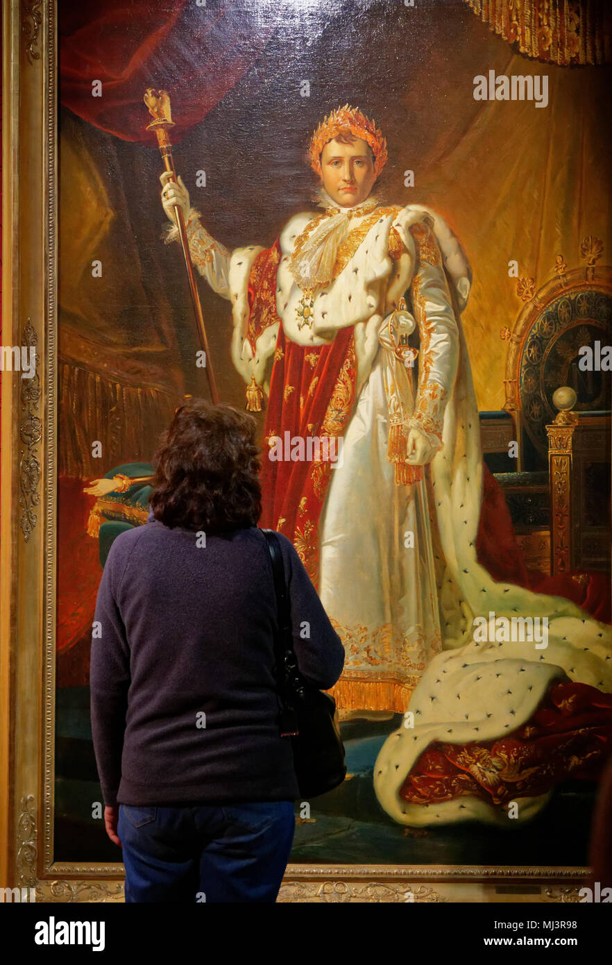A lady  looking at a large formal portrait of Napoleon in Ceremonial robes in the throne room of the Palais des Tuileries, by Francois Pascal Gerard Stock Photo