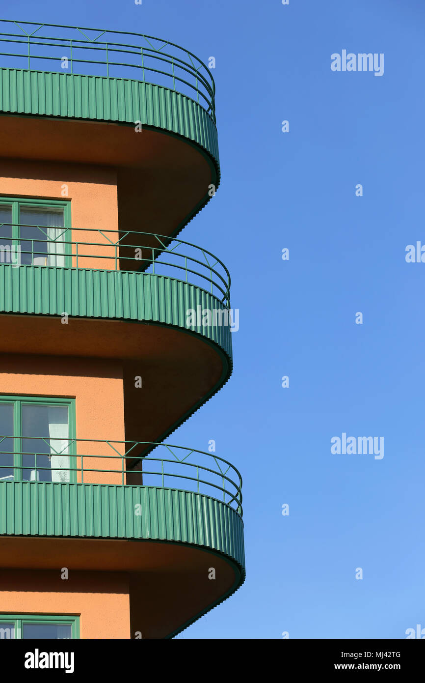 Building with green balconies against a blue sky. Stock Photo