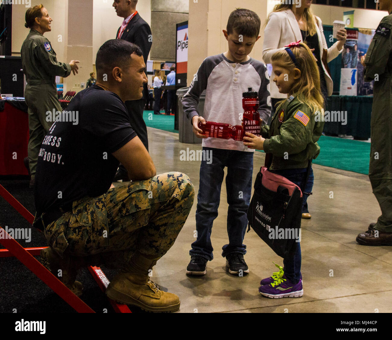 RENO, NV - 4-year-old Laren Brooks Leuschel and 6-year-old Gunner Leushchel from Greenville, South Carolina speak with Sgt. Angel Laracuente, a supply Marine for 12th Marine Corps District, at the Women in Aviation, International’s (WAI) 29th Annual Symposium in Reno, Nevada, March 23. Marines attended WAI to generate awareness for career opportunities in the Marine Corps while engaging with highly-qualified individuals and key influencers. The WAI’s 29th symposium falls on the 100 year anniversary of female service in the United States Marine Corps, a milestone celebrated by female aviators a Stock Photo