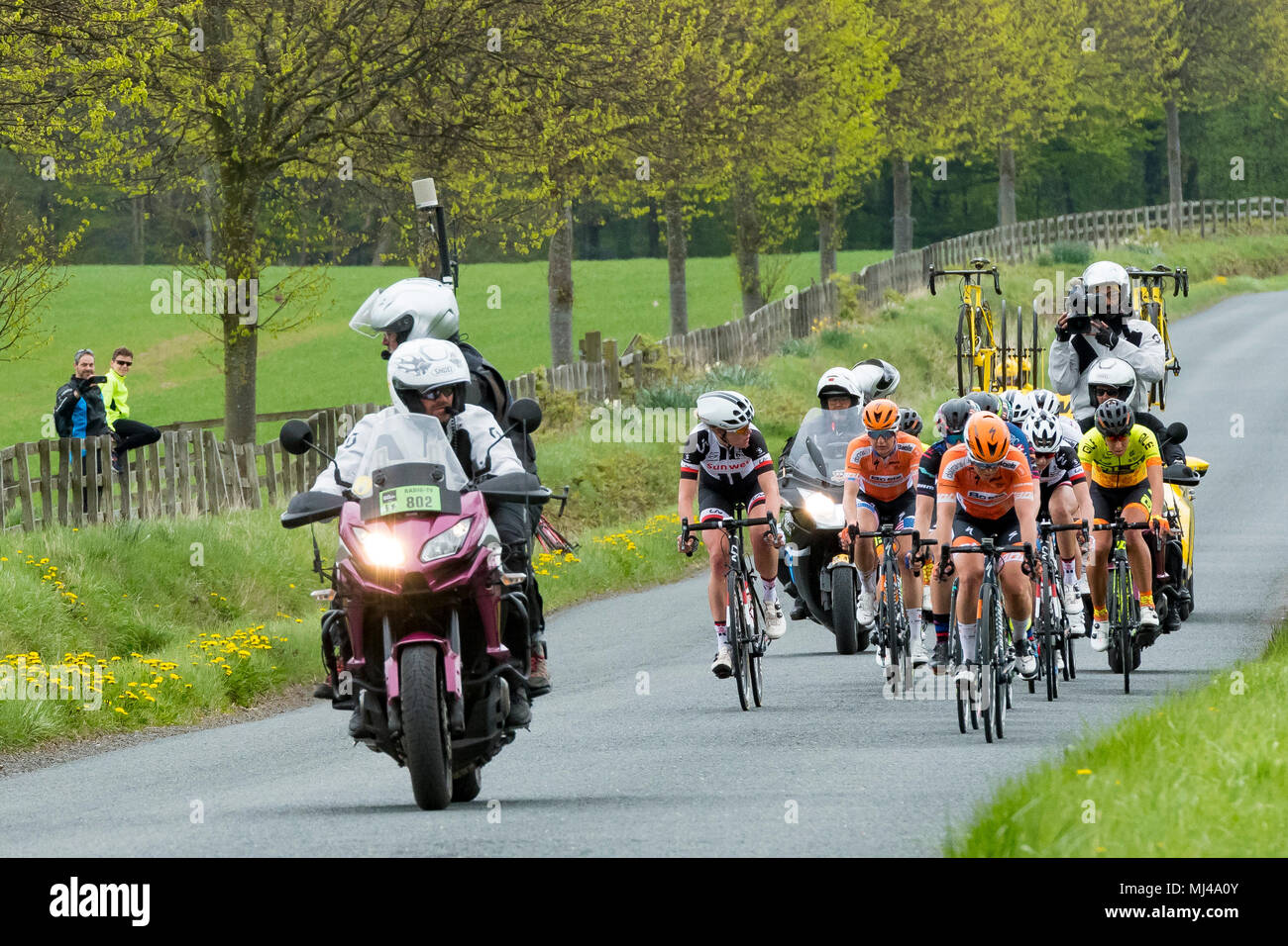 Near Denton, North Yorkshire, 4th May 2018. Group of female or women cyclists in the Asda Women's Tour de Yorkshire, racing past Denton Hall, on straight countryside lane near Ilkley, North Yorkshire, England, UK. TV camera crew on motor bikes in front & behind. 2 spectators watch from the roadside. Credit: Ian Lamond/Alamy Live News Stock Photo
