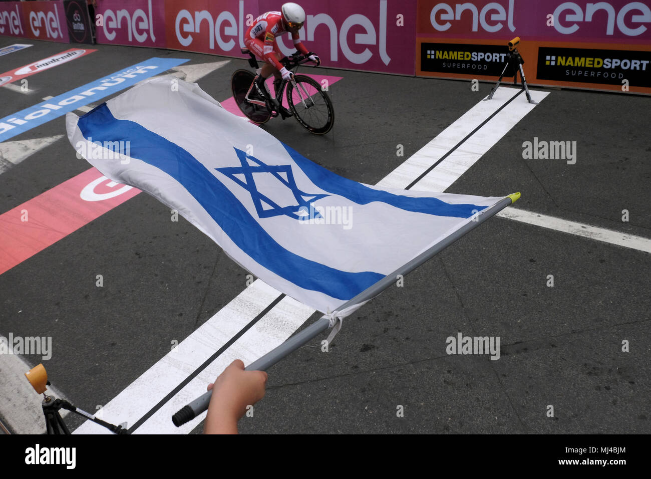 Jerusalem, Israel, 04 May 2018. A spectator waves with the Israeli flag as a cyclist from EF Education First-Drapac p/b Cannondale team crosses the finish line at the end of the 9,7 kilometers individual time-trial during the 1st stage of the 101st Giro d'Italia, Tour of Italy taking place in Jerusalem. The race's 'Big Start', beginning today, marks the first time any of cycling's three major races -- the Giro, Tour de France and Vuelta a Espana -- will begin outside of Europe. Credit: Eddie Gerald/Alamy Live News Stock Photo