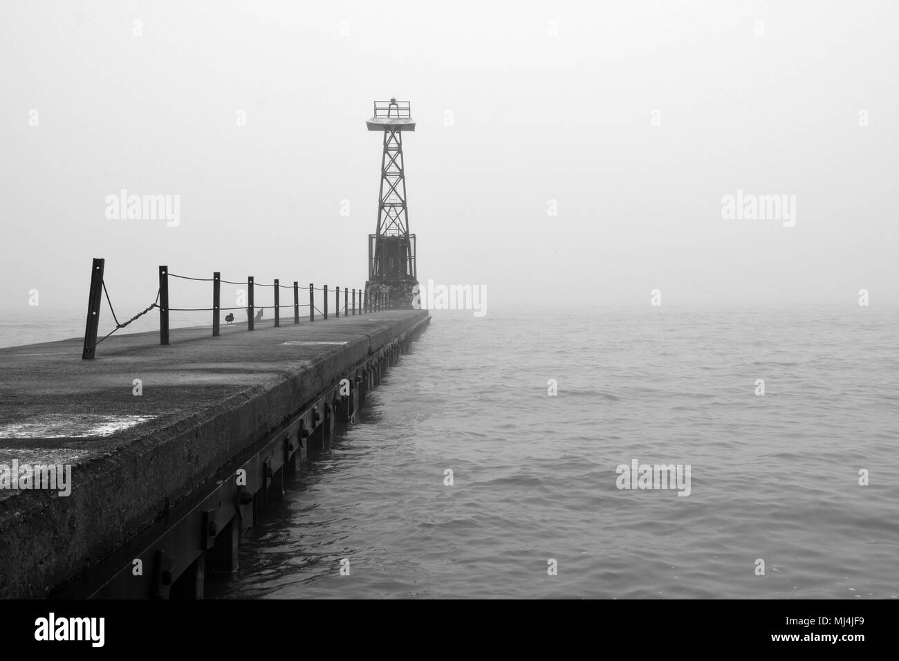 Fog and rain create poor visibility at the Foster Avenue Beach break wall signal tower on Lake Michigan in Chicago's north side Uptown neighborhood Stock Photo