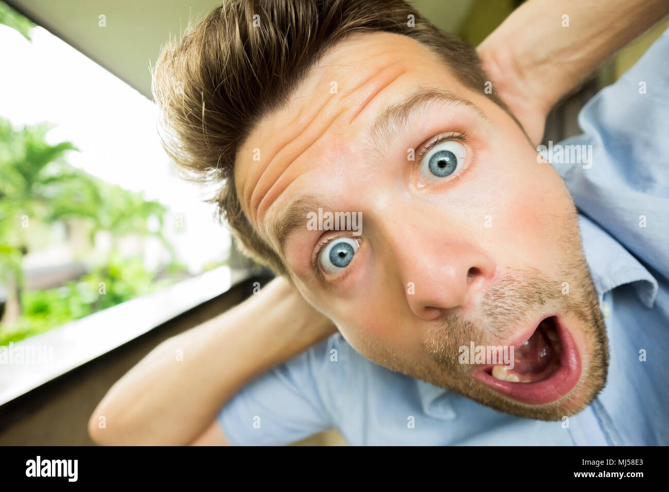 Panic man is shocked. His face is close to camera. He is opening his mouth in surprise Stock Photo