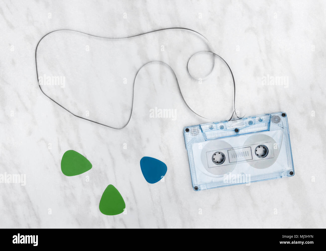 Blue audio tape and guitar picks on marble background. Stock Photo