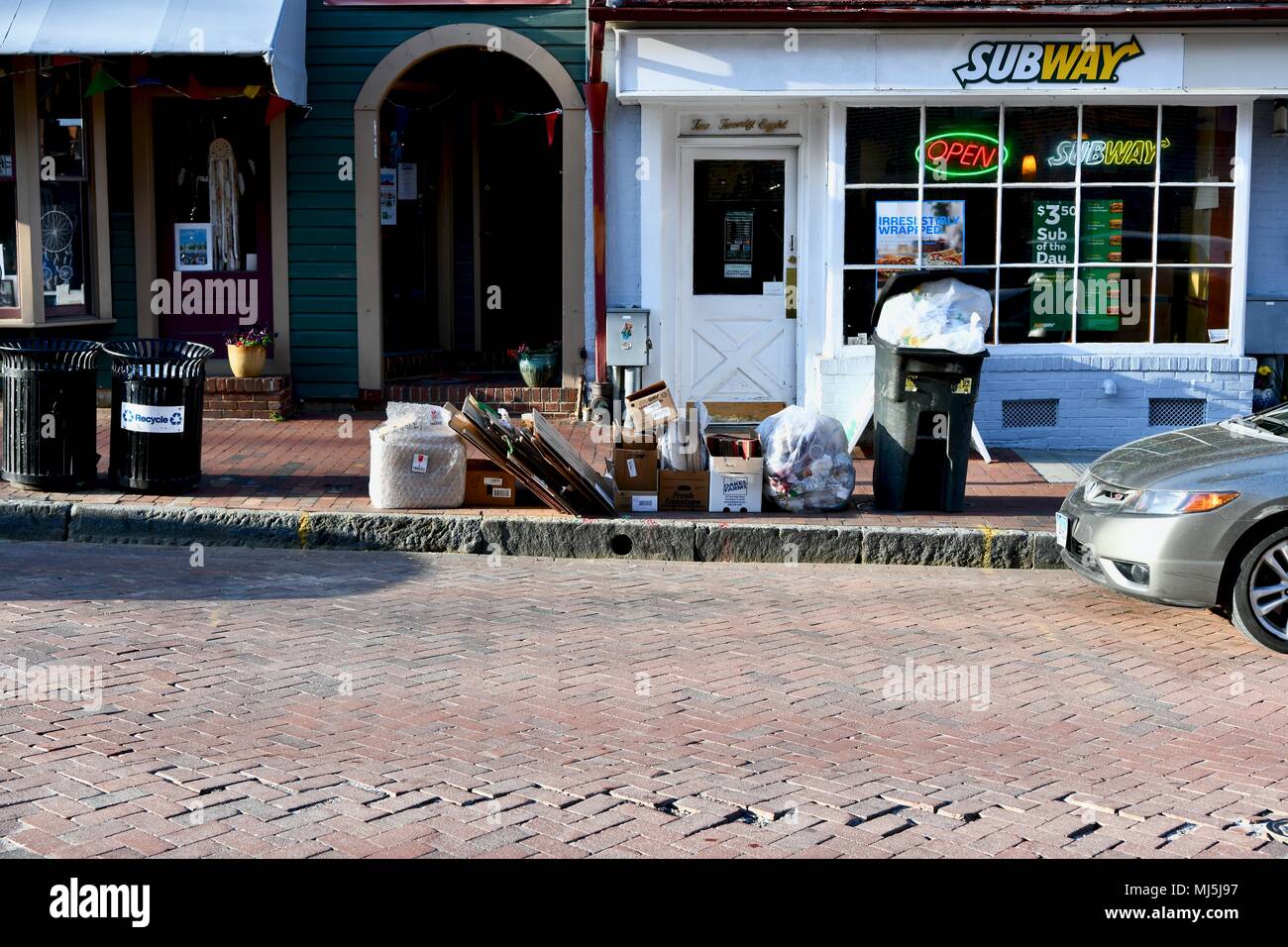 Trash and recycling piled up on the sidewalk outside a subway restaurant in Annapolis, MD, USA Stock Photo