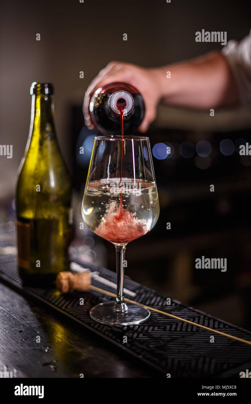 Bartender prepares an alcoholic cocktail based on champagne with strawberry syrup Stock Photo