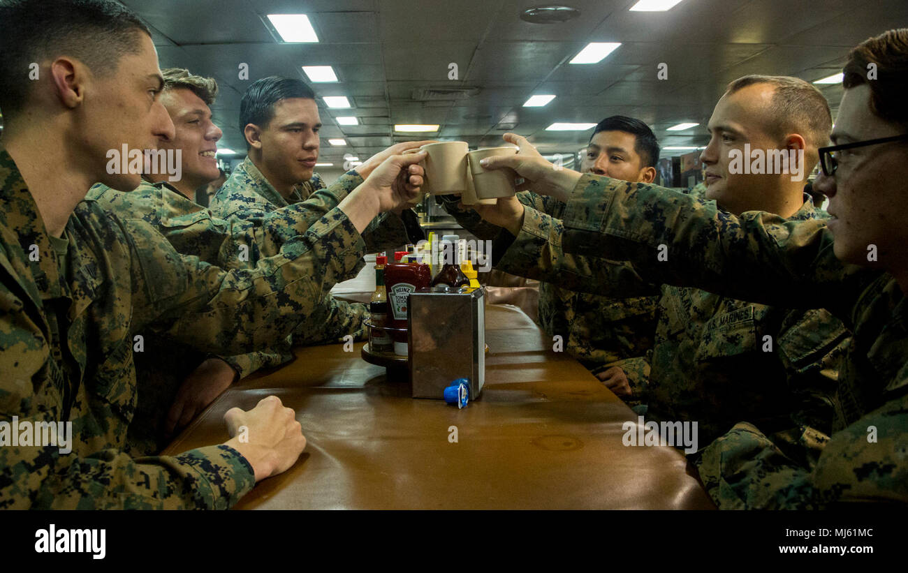Cpl. Jesse Coleman, armorer; Cpl. Seth Roses, squad leader; Cpl. Dimitric Lozano, fire team leader; Lance Cpl. Tyler Johnson, fire team leader; Lance Cpl. Kacie Crossland, fire team leader; and Cpl. Matias Felipe, fire team leader, Lima Company, Battalion Landing Team 3/1,  toast during dinner aboard the Wasp-class amphibious assault ship USS Essex (LHD 2), March 24, 2018. The Essex Amphibious Ready Group and 13th Marine Expeditionary Unit fully integrated for the first time before their summer deployment. Amphibious Squadron, MEU integration training is a crucial pre-deployment exercise that  Stock Photo