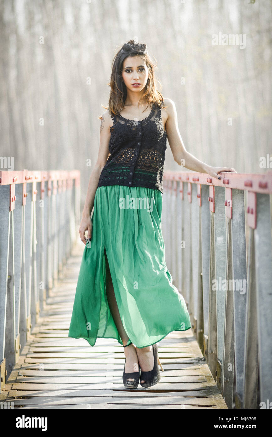 Portrait of beautiful young woman wearing long dress in a rural bridge Stock Photo