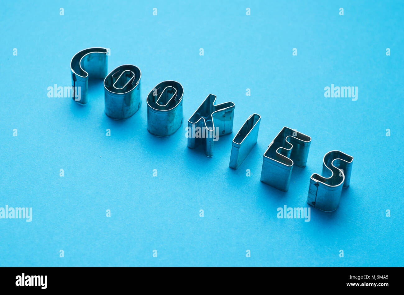 Cookies word written with cookie cutters molds over blue background Stock Photo