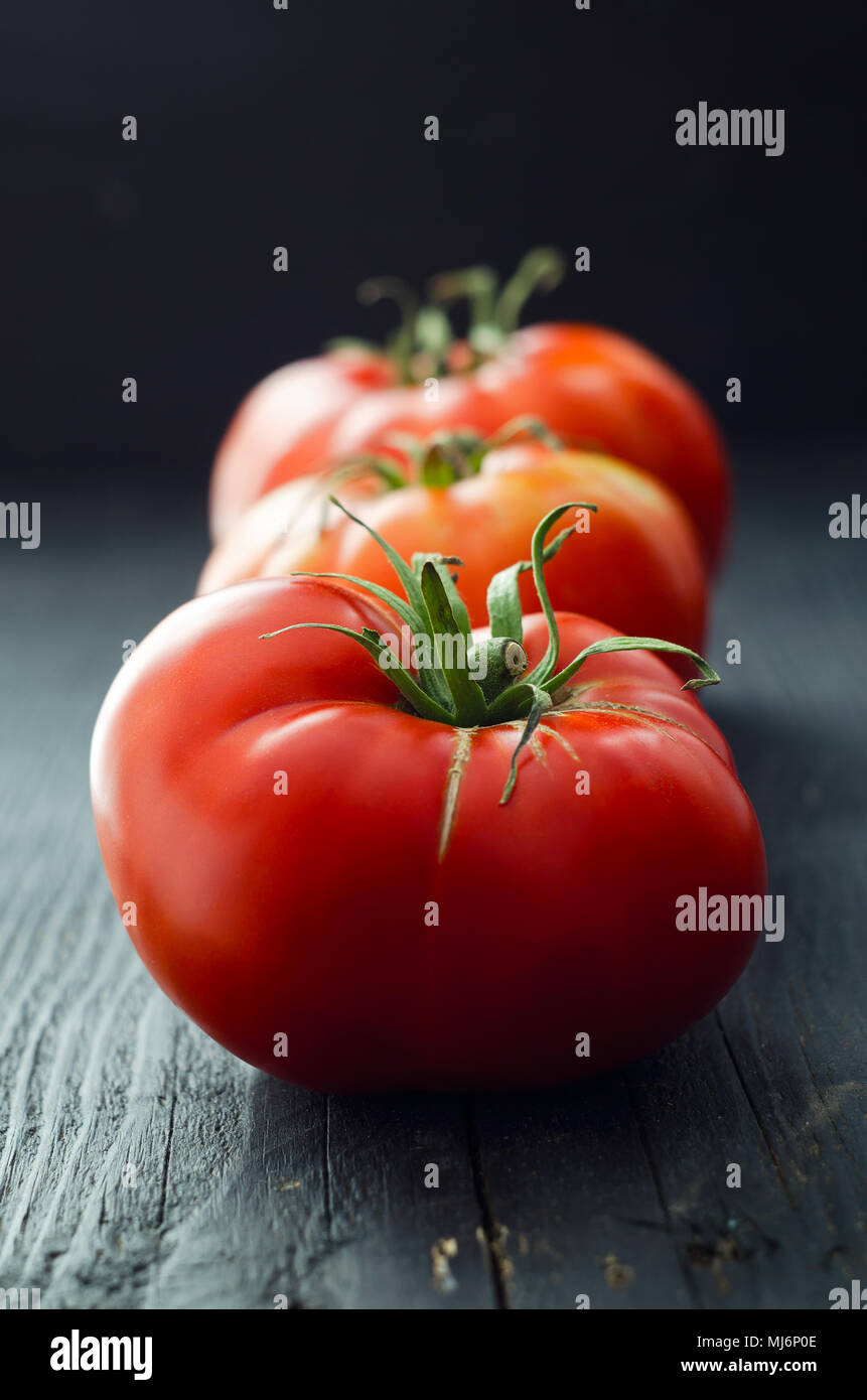 Organic tomatoes over dark black wooden table Stock Photo - Alamy