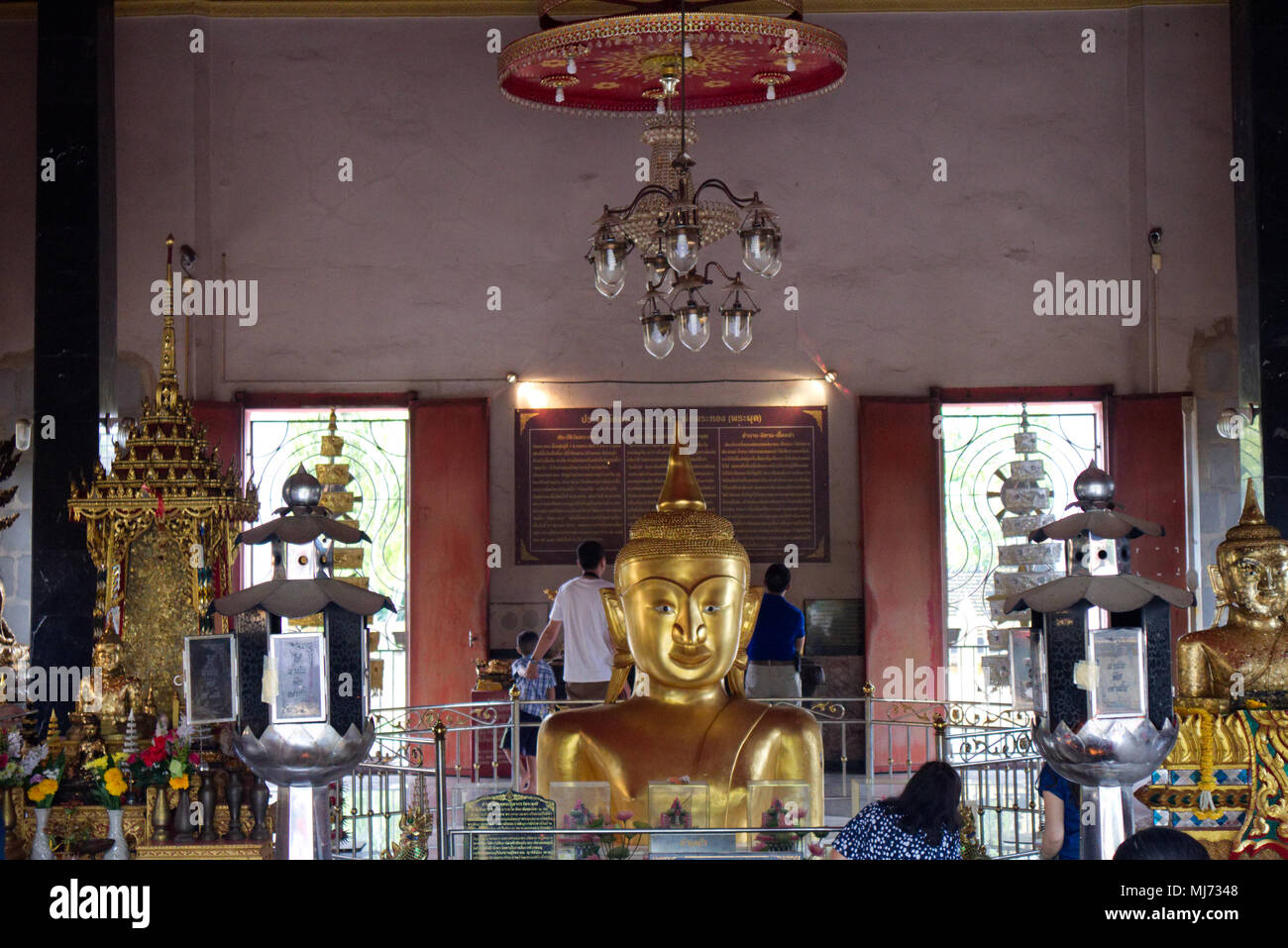 Thaland, Phuket / Thailand  - April 11 2018 : A young man is posing for a photograph in front of a gold statue of Buddha in the Wat Phra Tong Temple Stock Photo