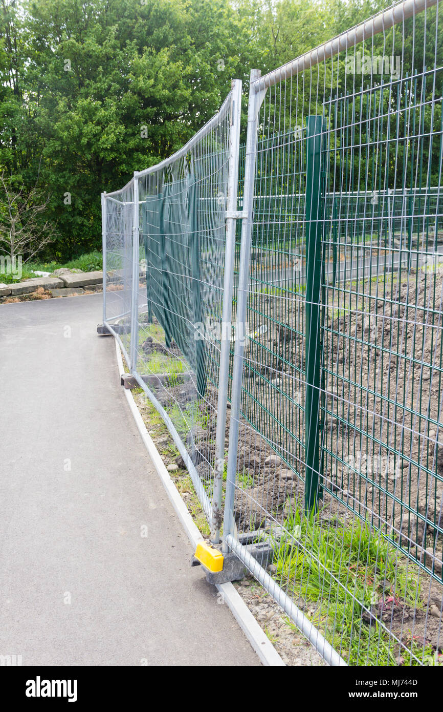 Temporary wire mesh fencing separating a surfaced footpath from a construction site. Stock Photo