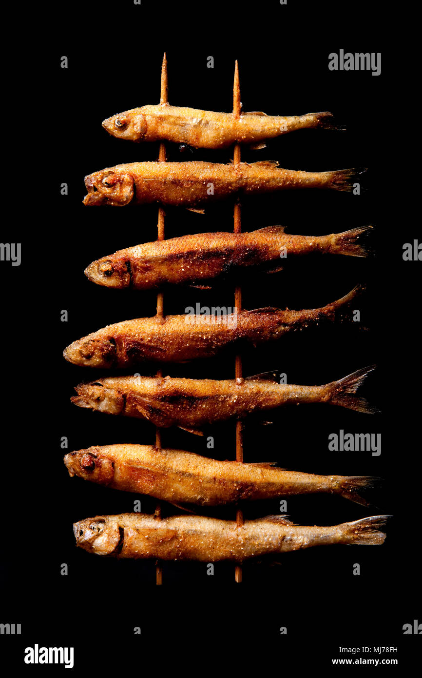 Sand smelts, Atherina presbyter, that have been skewered on bamboo kebab skewers and deep fried. They are a small seafish sometimes found in large sho Stock Photo