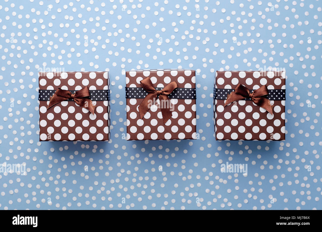 Christmas Gift Boxes with snow confetti in a row over blue background, above view Stock Photo