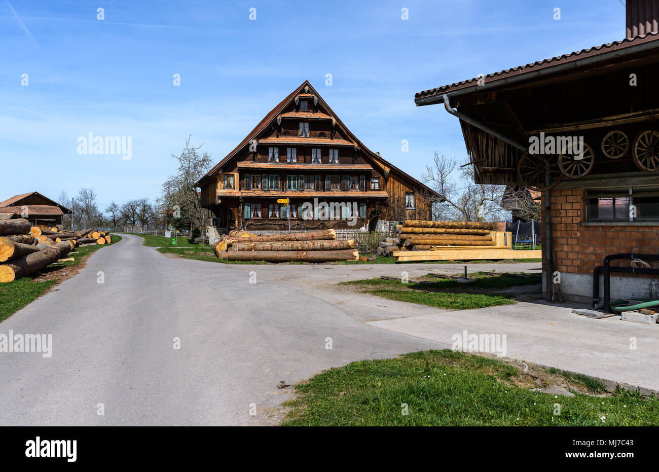 Traditional Swiss house farm with sawmill barn, log timber in front of it near Menzingen, Central Switzerland on a clear sunny spring day Stock Photo