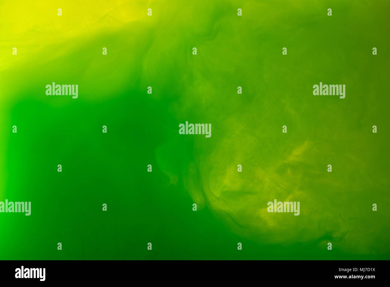 full frame image of mixing of green and yellow paints splashes in water ...