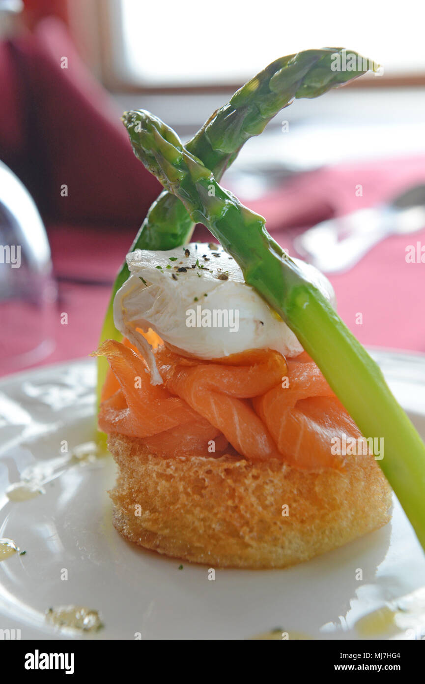 Salmon dish with egg and asparagus on a table in a restaurant Stock Photo