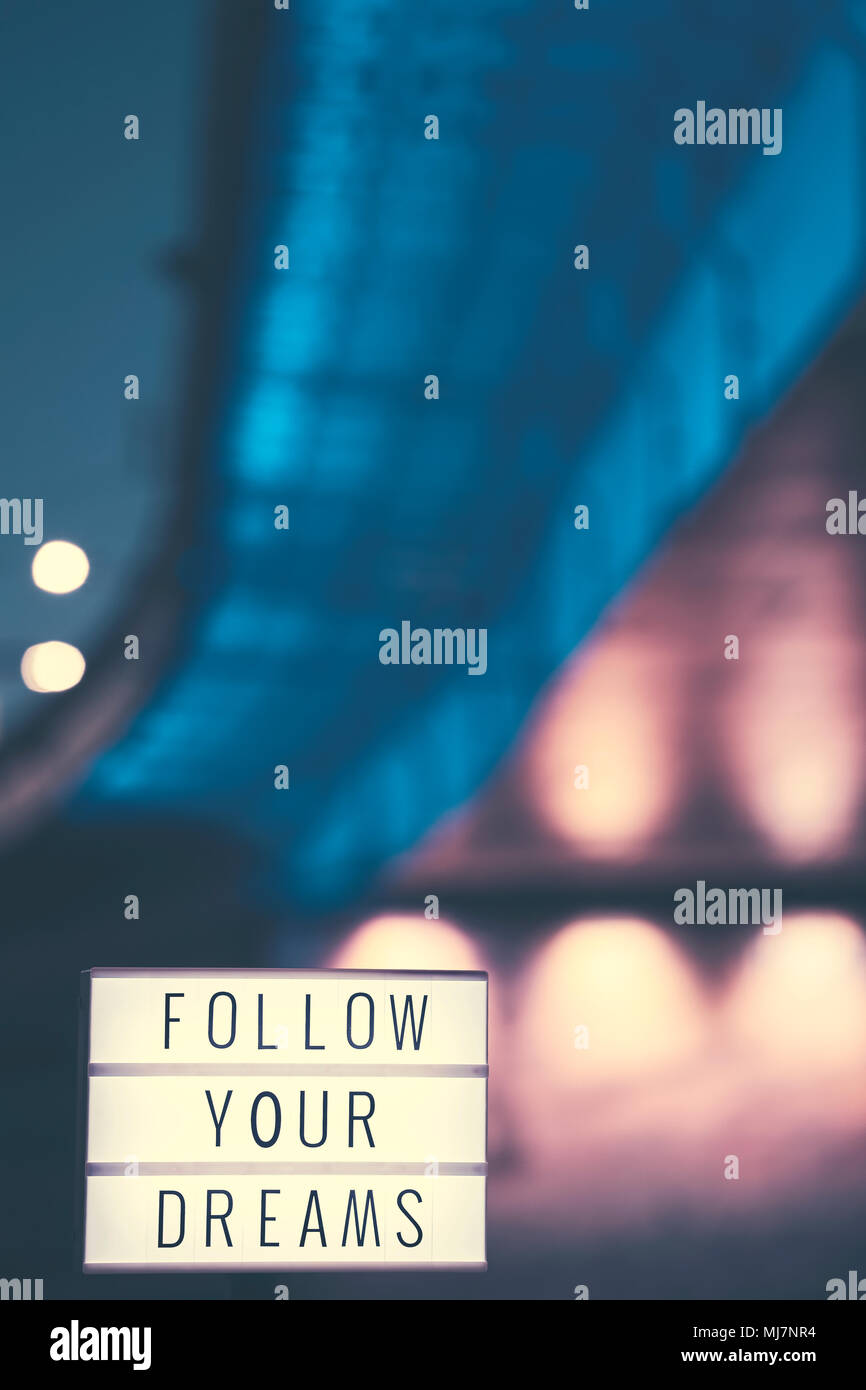 Follow Your Dreams inspirational life quote text in lightbox, city lights in background, color toned picture. Stock Photo