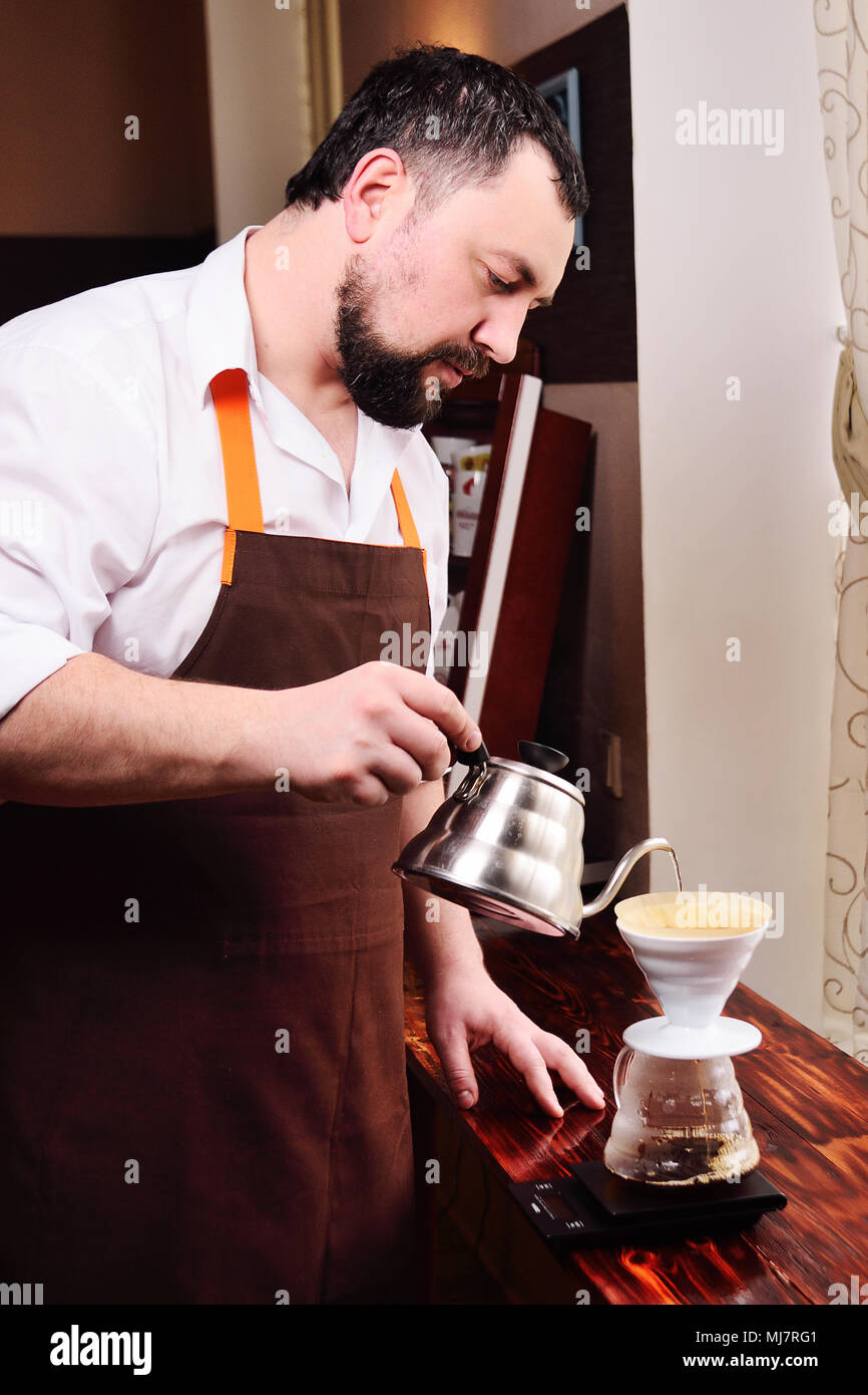 barista or coffee barman prepares coffee by an alternative method of