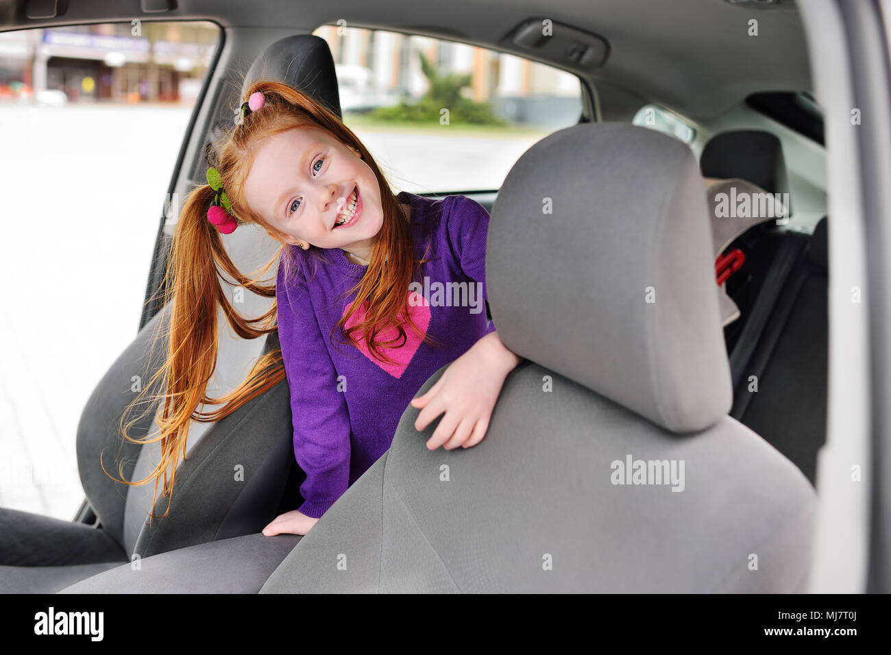 cute red-haired girl smiling in car salon Stock Photo - Alamy