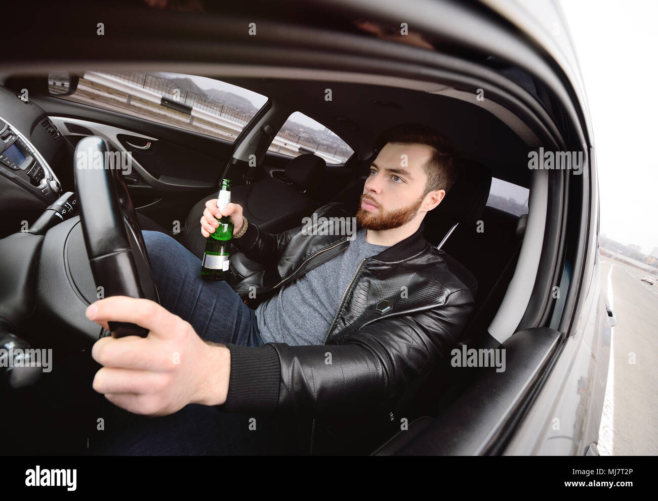Drunk man with a bottle of beer driving a car Stock Photo - Alamy