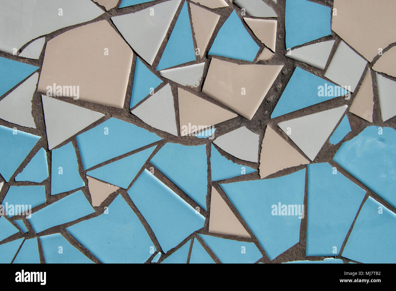 background with Broken tile mosaic in blue and beige colors on the exterior facade of a building. Stock Photo