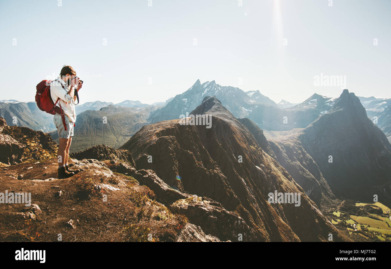 Man photographer with backpack and camera taking photo of aerial mountains landscape Travel Lifestyle hobby concept adventure active vacations outdoor Stock Photo