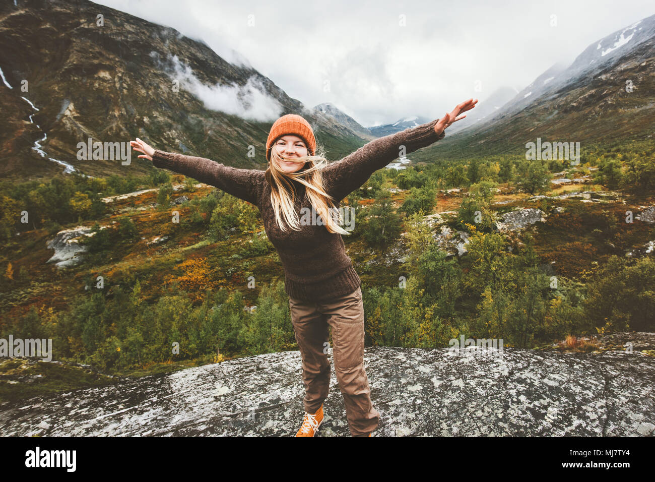 Happy woman raised hands walking in forest mountains enjoying view Travel adventure lifestyle concept active vacations in Norway Stock Photo