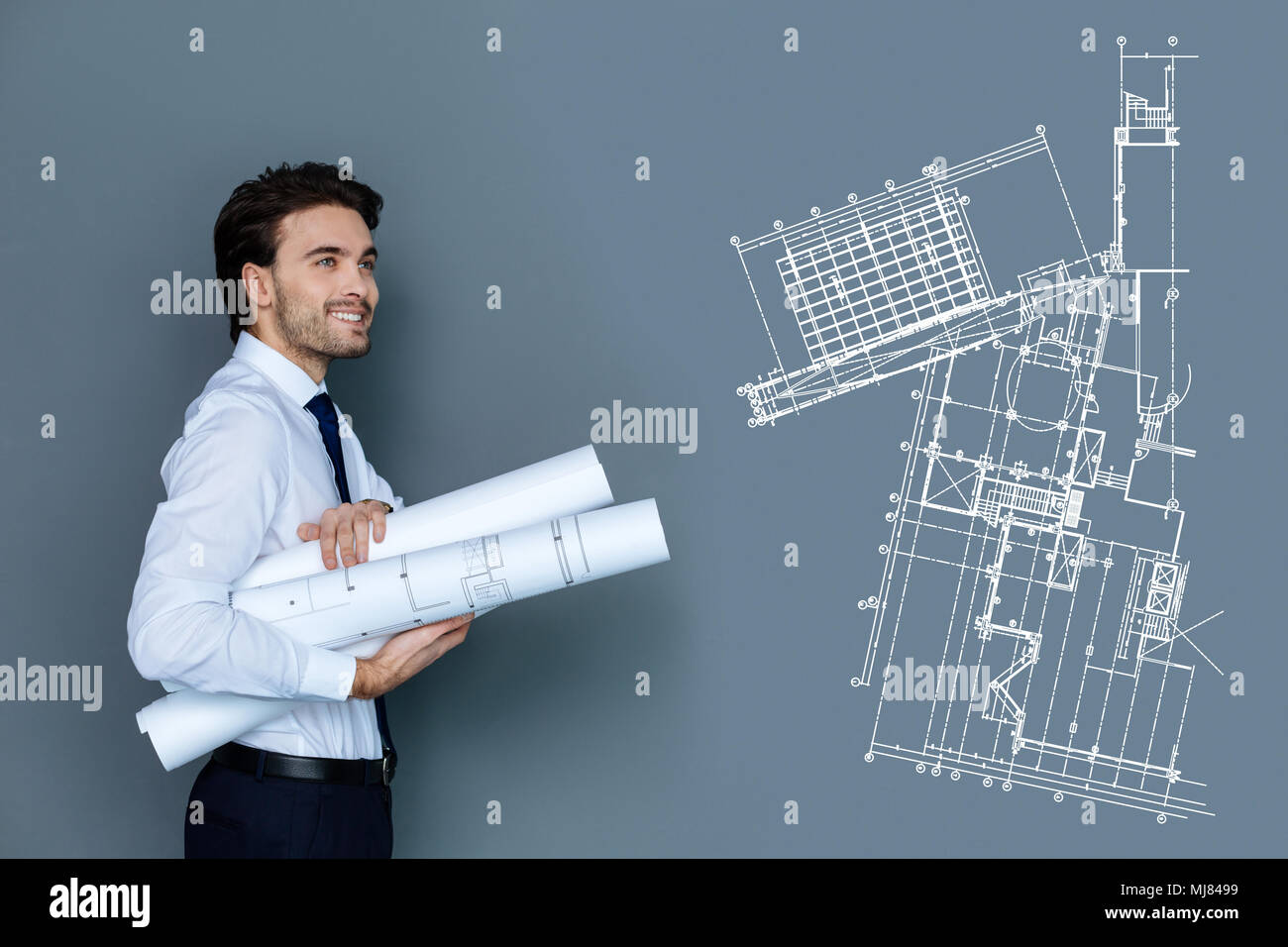 Happy young engineer smiling while carrying graphics to his colleagues Stock Photo