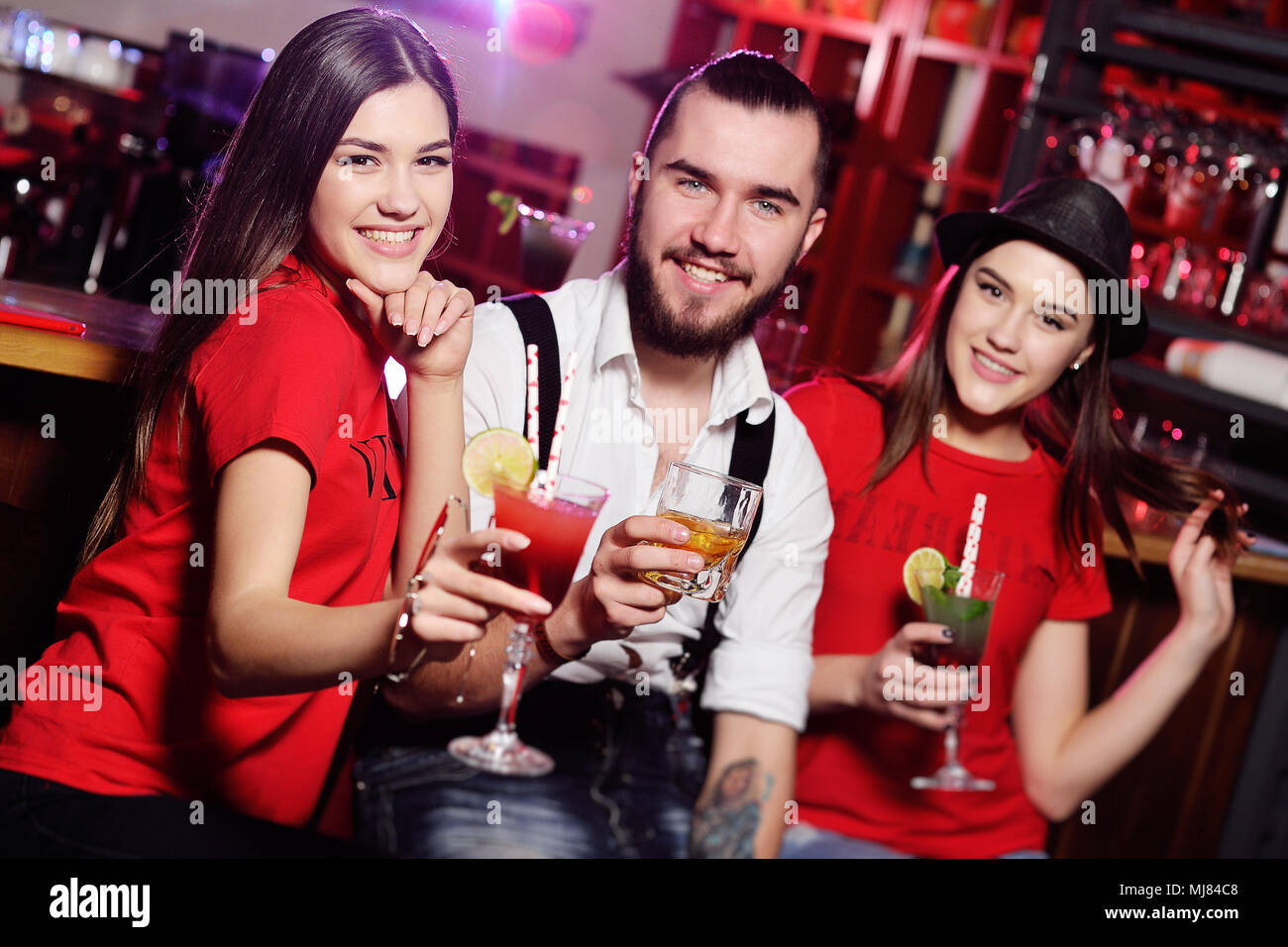 three friends cute guy and two attractive young girls at a party