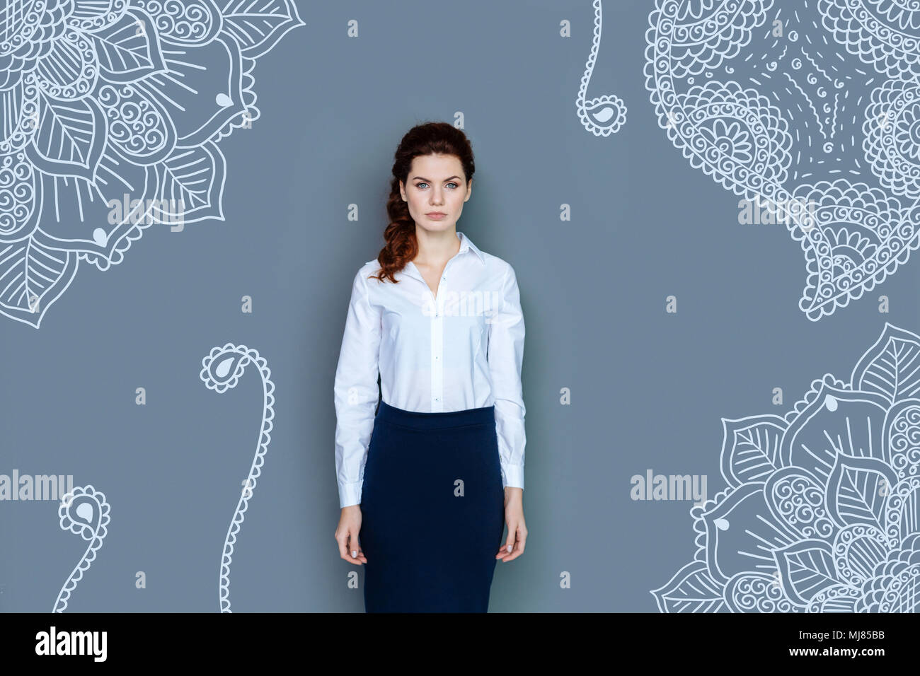 Serious business woman standing against grey background Stock Photo - Alamy